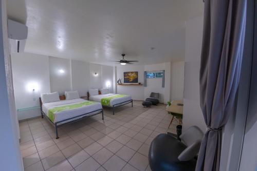 a living room with two beds and a couch at Casa Verde Hotel - Steps to the Beach, Pool, Restaurant & Bar in Rincon