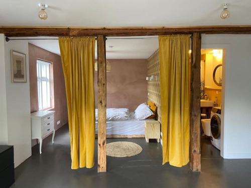 a bedroom with a bed with yellow curtains at Steinholt, charming & just renovated apartment ! in Seyðisfjörður