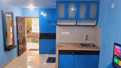 a kitchen with blue cabinets and a sink at Godwill Kimo Guest house Seraulim in Madgaon