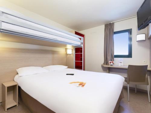 Habitación de hotel con cama blanca grande y escritorio. en Première Classe Chalon Sur Saône, en Chalon-sur-Saône