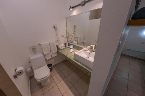 a bathroom with a sink and a toilet and a mirror at Casa Verde Hotel - Steps to the Beach, Pool, Restaurant & Bar in Rincon