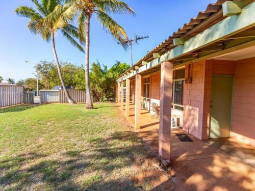 una casa con un porche con una palmera en Cosy unit by the beach, en Port Hedland