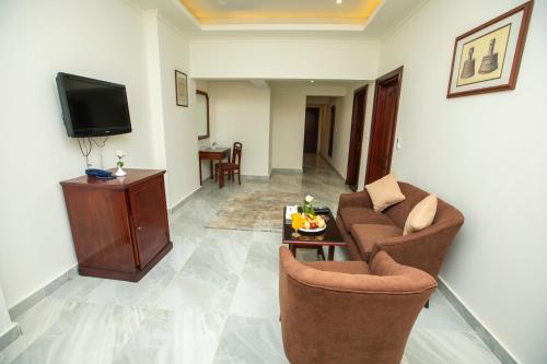 a living room with two chairs and a tv at AIFU Hotel El Montazah Alexandria in Alexandria
