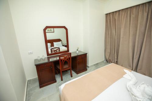 a bedroom with a bed and a mirror and a chair at AIFU Hotel El Montazah Alexandria in Alexandria