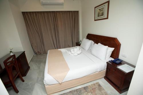 a bedroom with a large white bed and a night stand at AIFU Hotel El Montazah Alexandria in Alexandria