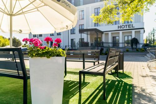 a couple of benches and an umbrella and flowers at Hotel Przy Solankach in Grudziądz