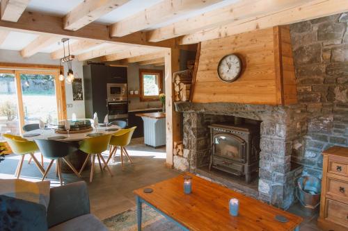 a living room with a stone fireplace with a clock at Chalet Dranse Winter Ski Summer Vtt Hot Tubsauna in Saint-Jean-dʼAulps