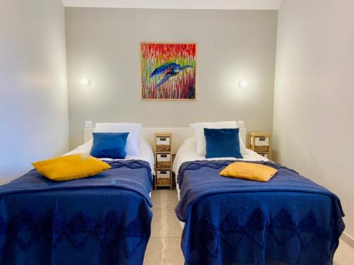1 dormitorio con 2 camas con sábanas azules y una pintura en Mas de Veyras - Gîtes 5 étoiles en Ardèche, en Lachapelle-sous-Aubenas