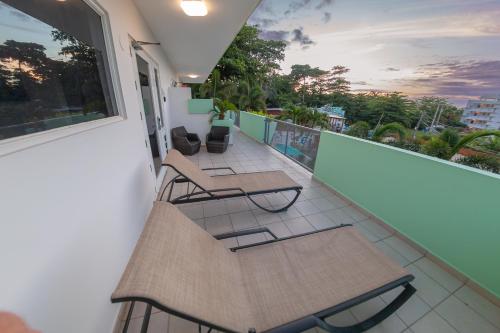 a balcony with chairs and tables on a building at Casa Verde Hotel - Steps to the Beach, Pool, Restaurant & Bar in Rincon