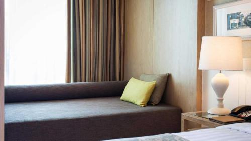 a hotel room with a couch with a yellow pillow at Amari Hua Hin in Hua Hin