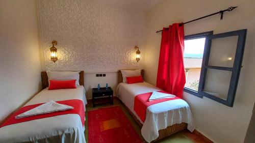 two beds in a room with a window at Auberge Kasbah Ennakhile in Nkob