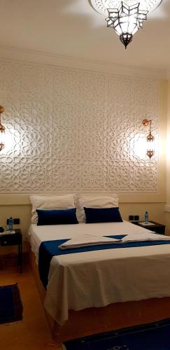 a bedroom with a bed and a chandelier at Hotel Kasbah Ennakhile in Nkob