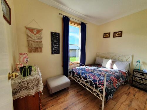 a bedroom with a bed and a window and a chair at Ruby's Cottage Farm Stay in Port Arthur