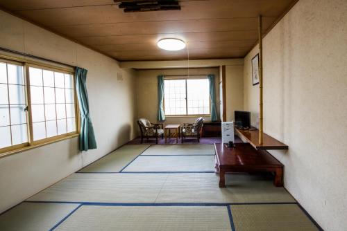 Hotel Tsustujisou في كيتامي: غرفة فارغة مع طاولة وكراسي ونوافذ