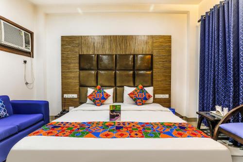 1 dormitorio con 1 cama grande y 1 sofá azul en FabHotel The Residency DLF Galleria, en Gurgaon