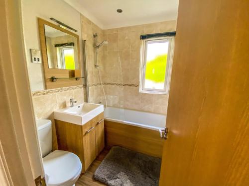 a bathroom with a toilet and a sink and a mirror at Immaculate 3-Bedroom Private Lodge near York in York