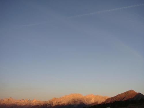 a group of mountains with the sun shining on them at Berghotel Jochgrimm - Your Dolomites Home in Varena