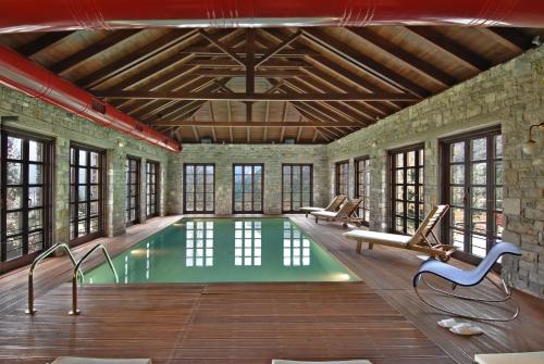 an indoor pool with lounge chairs and a swimming pool at Aristi Mountain Resort in Aristi