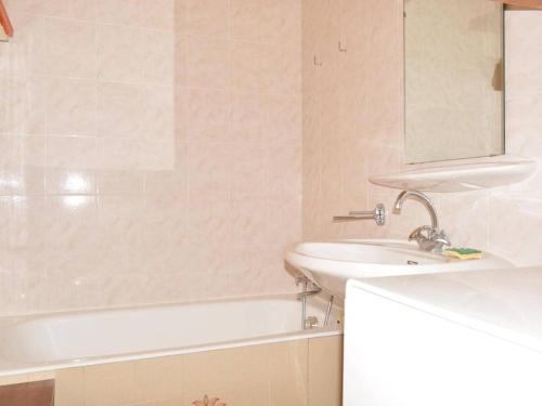 uma casa de banho com um lavatório, uma banheira e um espelho. em Appartement Le Grand-Bornand, 1 pièce, 6 personnes - FR-1-241-5 em Le Grand-Bornand