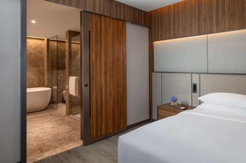 a bedroom with a bed and a bathroom with a tub at Hyatt Regency Trivandrum in Trivandrum