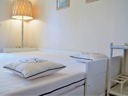 - un lit blanc avec 2 oreillers dans l'établissement Appartement 3 pièces avec piscine et garage, proche plage - FR-1-251-6, à Bormes-les-Mimosas