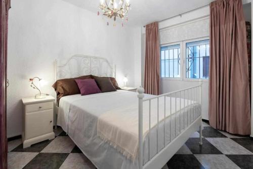 sypialnia z białym łóżkiem i żyrandolem w obiekcie Apartamento Gallo Rojo w mieście El Campello