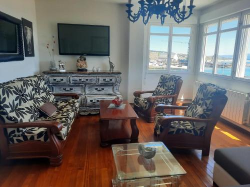 a living room with couches and a flat screen tv at Apartamentos Puerto de Aguiño in Couso