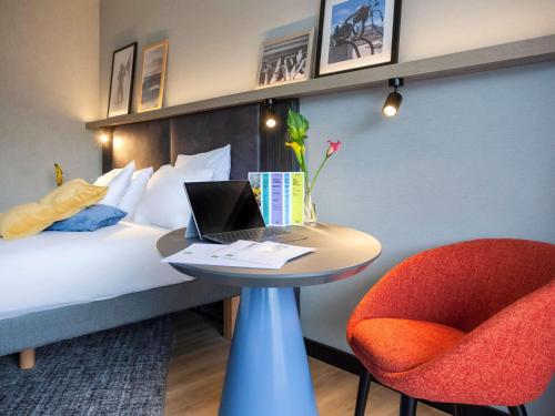 ein Hotelzimmer mit einem Bett und einem Tisch mit einem Laptop in der Unterkunft ibis Styles Den Haag Scheveningen in Scheveningen
