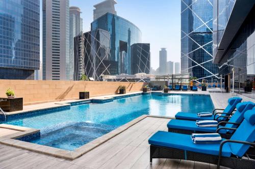a lap pool on the roof of a building with chairs at Wyndham Doha West Bay in Doha