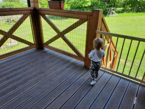 a little boy standing on a deck with a fence at Szychów z widokiem in Stara Łomnica