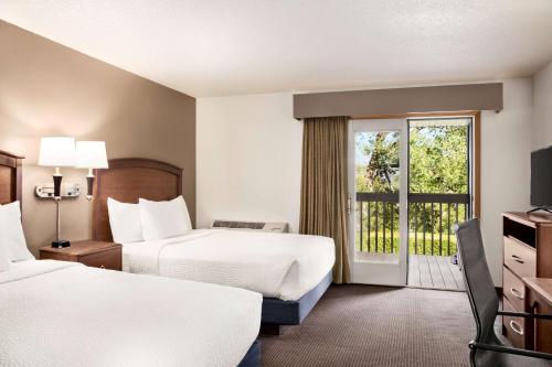um quarto de hotel com duas camas e uma varanda em AmericInn by Wyndham Baudette em Baudette