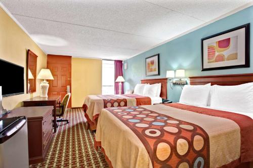 a hotel room with two beds and a flat screen tv at Super 8 by Wyndham Raleigh Downtown in Raleigh