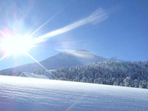 a snow covered slope with the sun in the background at Berghotel Jochgrimm - Your Dolomites Home in Varena