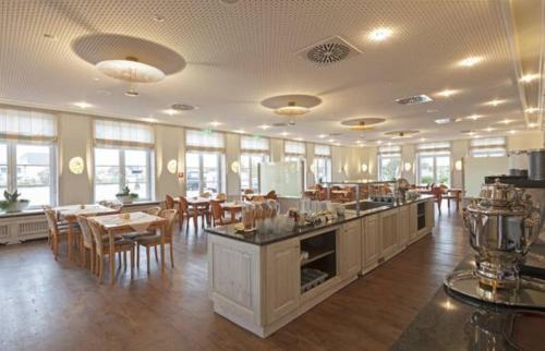 uma grande sala com mesas e cadeiras num edifício em Hotel Neuwarft Altbau em Dagebüll