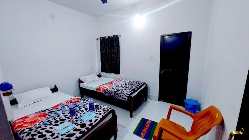 Habitación con 2 camas y una silla. en Nilam Guest House, en Bodh Gaya
