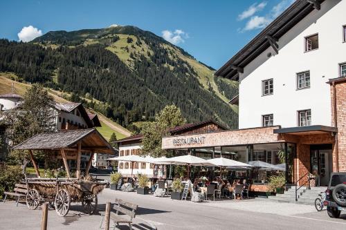 a town with a horse drawn carriage in front of a mountain at Posthotel Lechtal, Arlberg in Holzgau