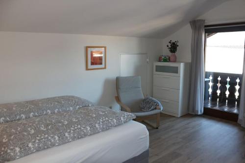 een slaapkamer met een bed, een stoel en een raam bij Wohnung Bergtraum inmitten der Ammergauer Alpen in Oberammergau