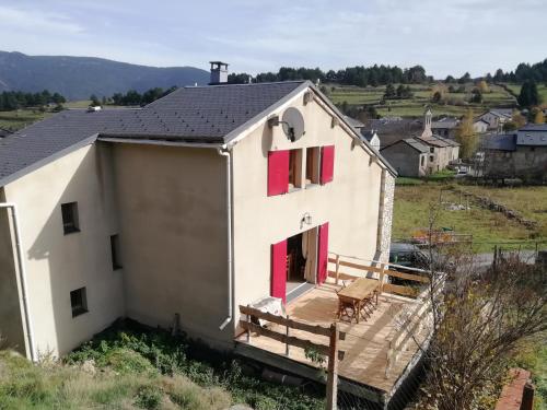 een wit huis met rode deuren en een terras bij Maison de montagne dans charmant village du Capcir in Fontrabiouse