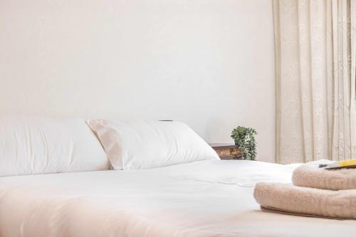 a white bed with white sheets and pillows on it at Ca La Valls - Casa céntrica ideal para familias in Tortellá