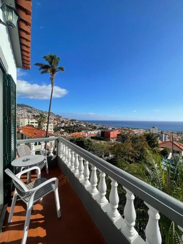 a balcony with a chair and a table and a palm tree at Valhalla Panorama in Funchal