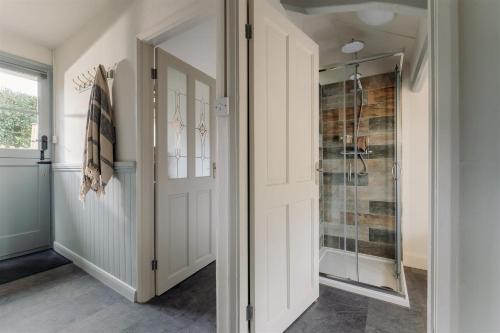 a bathroom with a shower and a glass door at The Stables - Charming 15th-century rural bolthole in Newton Abbot
