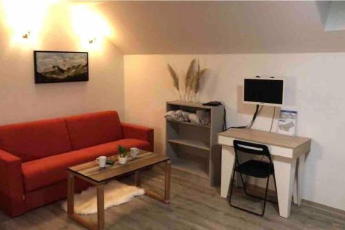 een woonkamer met een bank en een bureau met een televisie bij Au bout du bois Piscine sauna hammam accessible en saison et le logement accessible toute l annee in Les Déserts