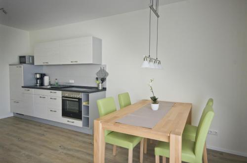 a kitchen with a wooden table and green chairs at Appartements Am Kurpark in Bad Windsheim