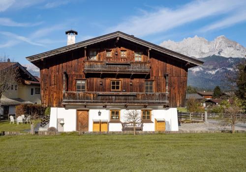 a large wooden barn with mountains in the background at Landhaus Ammer in Oberndorf in Tirol