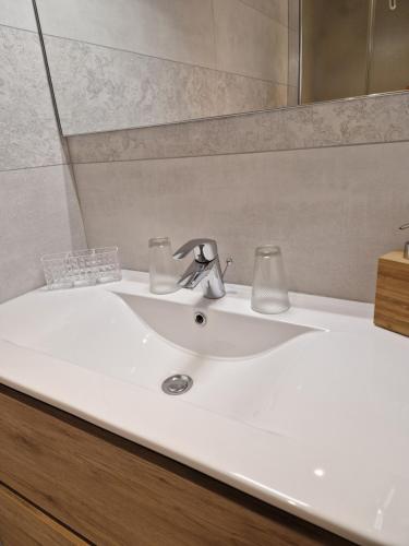 La salle de bains est pourvue d'un lavabo blanc et d'un miroir. dans l'établissement Hipster suites - Chez Axelle -, à Colmar