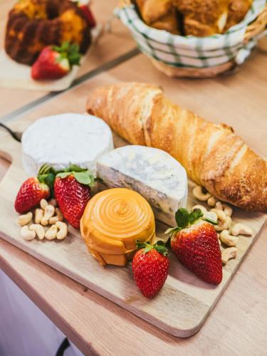 a cutting board with cheese and strawberries on a table at A MI KISHÁZUNK vendégház in Szomód