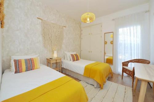 a bedroom with two beds and a table and a mirror at Tropical Pool View Cascais - Checkinhome in Cascais