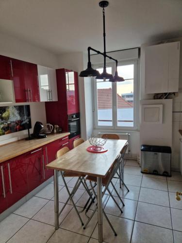 une cuisine avec une table en bois et des placards rouges dans l'établissement Hipster suites - Chez Axelle -, à Colmar