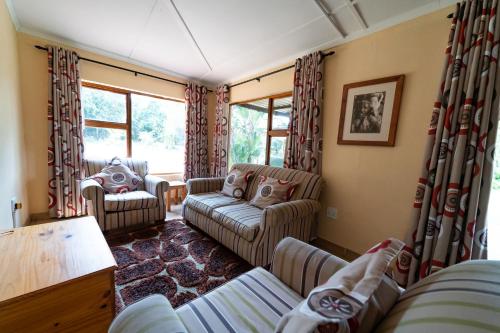 a living room with two couches and windows at Gooderson Bushlands Game Lodge in Hluhluwe