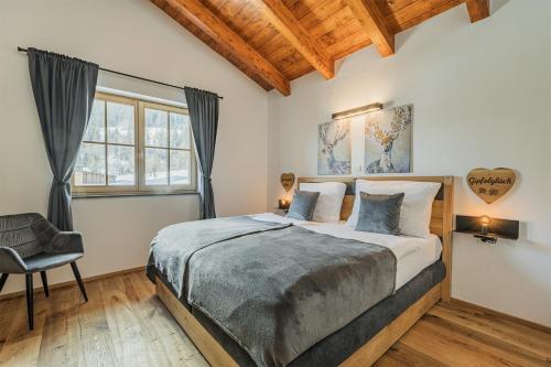 um quarto com uma cama grande e uma cadeira em Dachstein West Apartment T5 em Russbach am Pass Gschütt